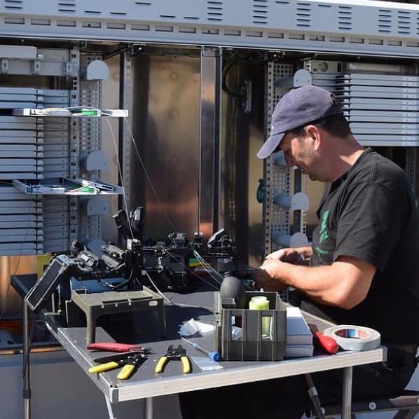 Techniker bei der Wartung eines MFG Gehäuses mit offenem Patchpanel im Außeneinsatz